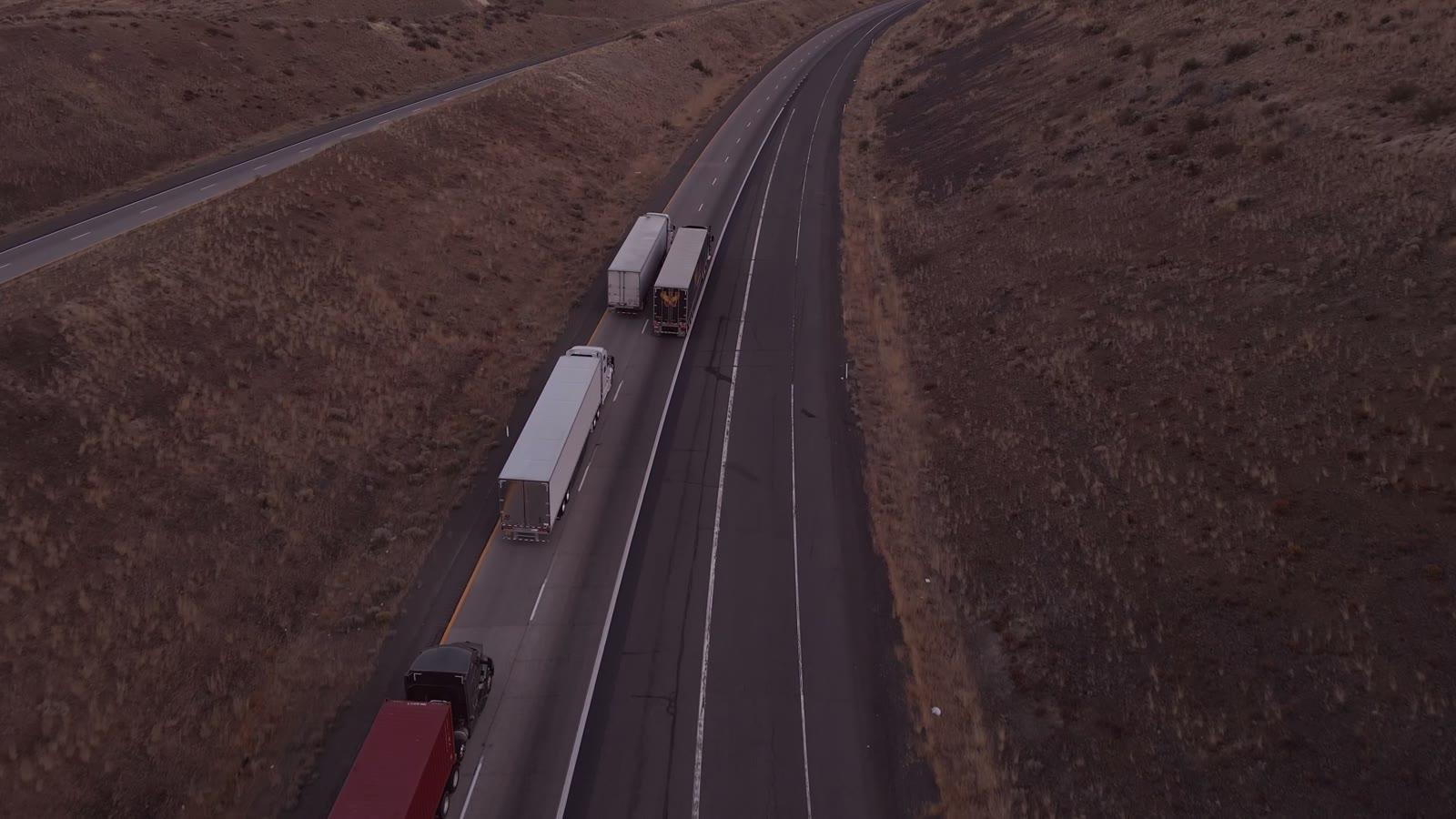 Semi trucks on a highway at dusk, seen from above